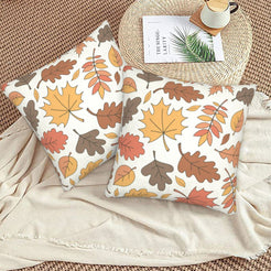 Set of two velvet pillow covers with cream autumn leaves and branches, styled on a woven chair