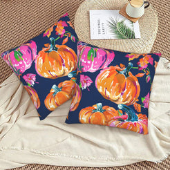 Set of two velvet pillow covers with navy pink and orange pumpkins, styled on a woven chair