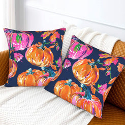 Set of two velvet pillow covers with navy pink and orange pumpkins, styled on a sofa