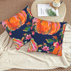 Set of two velvet pillow covers with navy large pumpkins and small flowers, styled on a woven chair