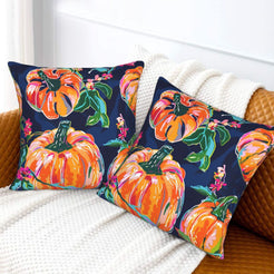 Set of two velvet pillow covers with navy pumpkins and autumn leaves, styled on a sofa