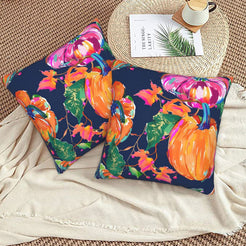 Set of two velvet pillow covers with navy mixed fall leaves and pumpkins, styled on a woven chair