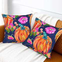Set of two velvet pillow covers with navy pumpkin and pink rose pattern, styled on a sofa