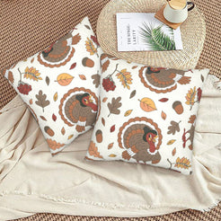 Set of two velvet pillow covers with cream turkeys and autumn leaves, styled on a woven chair