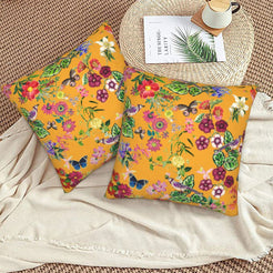 Tropical velvet pillow covers with mustard butterflies and flowers, styled on a woven chair