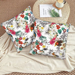Tropical velvet pillow covers with white colorful birds and flowers, styled on a woven chair