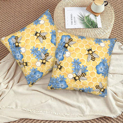 Velvet pillow covers with yellow honeycomb, bees and blue flowers, styled on a beige sofa