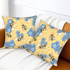 Velvet pillow covers with yellow honeycomb, bees and blue flowers, styled on a white sofa