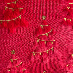Close-up of raised embroidery and woven surface on quilted polyester pillow cover with gold embroidered trees on red