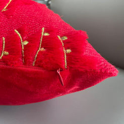 Close-up of hidden zipper and raised embroidery on quilted polyester pillow cover with gold embroidered trees on red