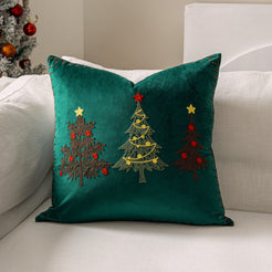 Green velvet pillow cover with embroidered Christmas trees on a sofa