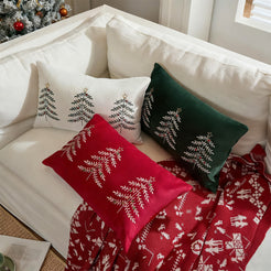 Red, green and ivory embroidered Christmas tree pillow covers styled on a sofa