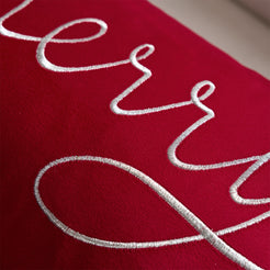 Close-up of white embroidered Merry script on red velvet
