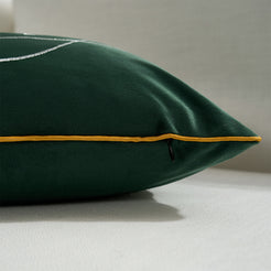 Hidden zipper and gold piped edge detail on a green velvet lumbar pillow cover