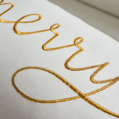 Close-up of gold embroidered Merry script on ivory velvet