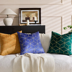 Embroidered velvet pillow covers with mustard, lavender and emerald geometric designs, styled on a cream sofa