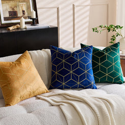Embroidered velvet pillow covers with mustard, royal blue and emerald geometric designs, styled on a cream sofa