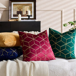 Embroidered velvet pillow covers with burgundy, mustard and emerald geometric designs, styled on a cream sofa
