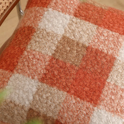Looped fabric texture close-up of bouclé-textured polyester pillow cover with rust orange, cream and taupe plaid