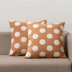 Loop-pile textured polyester pillow covers with raised white polka dots on warm tan, styled on a neutral sofa