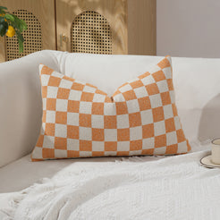 Orange and ivory checkerboard chenille lumbar pillow cover on a sofa