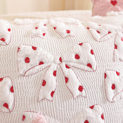 Close-up of raised bow embroidery on embroidered woven polyester pillow cover with white bows with red polka dots