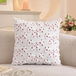 Embroidered woven polyester pillow covers with white bows with red polka dots, styled on a cream sofa