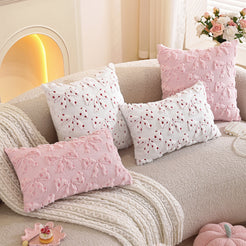 Embroidered woven polyester pillow covers with pink bow and heart designs, grouped on a cream sofa