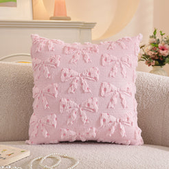 Embroidered woven polyester pillow covers with raised pink bows, styled on a cream sofa