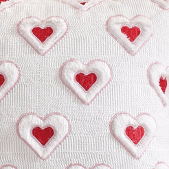 Close-up of raised heart embroidery on embroidered woven polyester pillow cover with raised red hearts on white
