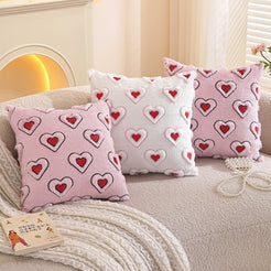 Embroidered woven polyester pillow covers with four pink bow and heart designs, grouped on a cream sofa
