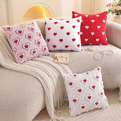 Embroidered woven polyester pillow covers with red and pink heart designs, grouped on a cream sofa