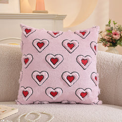 Embroidered woven polyester pillow covers with outlined red hearts on pink, styled on a cream sofa