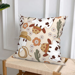 short-pile plush polyester pillow cover with cowboy ghost, hats, flowers and cactus on cream, styled on a woven chair
