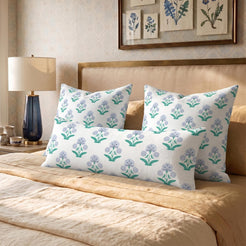 Long lumbar pillow cover with lavender-blue small floral sprigs, arranged with square covers on a bed
