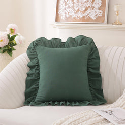 Dark green washed cotton pillow cover with ruffled edges on a sofa